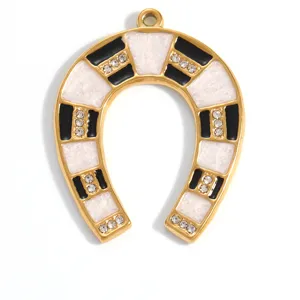 Macro detail of gold-plated horseshoe pendant with black and white enamel and rhinestones