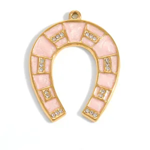 Detailed view of gold-plated horseshoe pendant with pink enamel and sparkling crystals