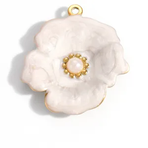 Detail macro view of white enamel flower pendant with pearl center and gold-plated edges
