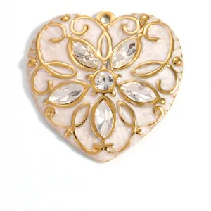 Close-up of gold-plated heart pendant with white enamel and sparkling crystals