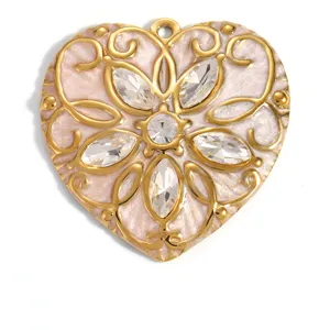Macro view of a gold-plated heart pendant with pink enamel and crystal flower detail