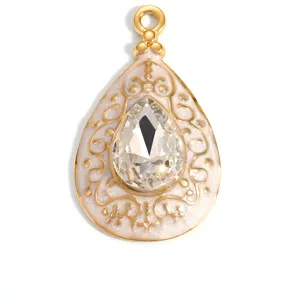 Detailed close-up of a gold-plated teardrop pendant with enamel and clear crystal.