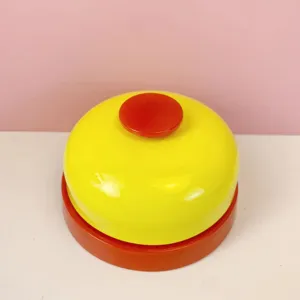 Detailed view of the bright yellow and red metal call bell, perfect for desk or pet training use.