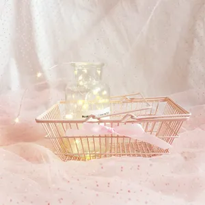 Pink metal storage basket for desktop organization, cute aesthetic photo prop detail.