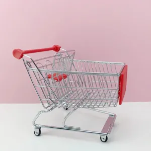 Détail de mini caddie en métal, poignée rouge et panier en fil pour décoration de table.