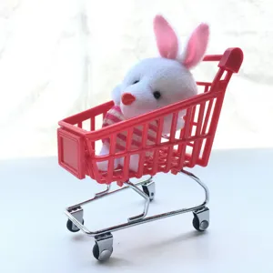 Gros plan d'un mini chariot de courses rose mignon contenant un lapin floconné comme décoration.
