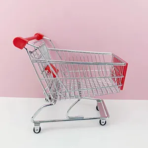 Détail de mini chariot de courses en métal, poignée rouge, vaisselle créative.