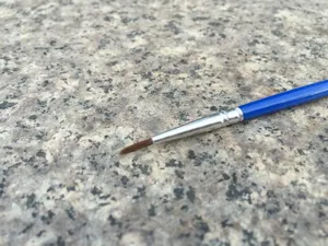 Feiner Pinsel mit blauem Griff und weichen Borsten für präzise Malerei und Bastelarbeiten.