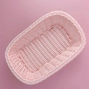 Panier de rangement tressé en rotin plastique rose, organisateur de bureau compact.