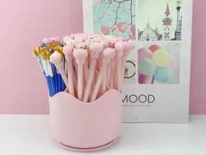 Détail de porte-stylo rotatif rose affichant un rangement de bureau mignon avec stylos.