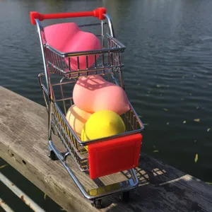 Closeup view of colorful makeup sponge set displayed inside a cute miniature shopping cart prop.