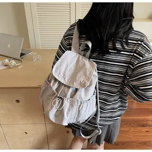Lifestyle-Detail eines hellgrauen Nylon-Rucksacks mit Kordelzug und MUTING-Stickerei.