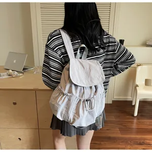 Rückansicht eines hellgrauen Nylon-Rucksacks mit Kordelzug in einem modernen Zimmer