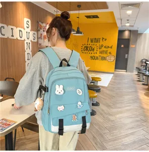 Détail d'un sac à dos scolaire bleu avec des écussons mignons porté par un modèle