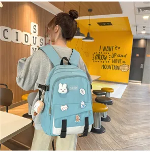 Adolescente portant un sac à dos bleu clair avec des écussons de dessins animés dans un café.
