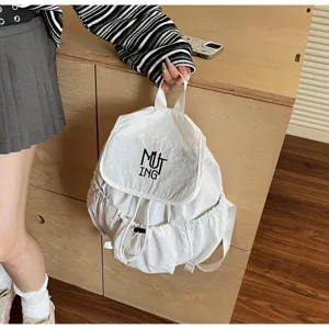 Detailansicht eines weißen Nylon-Rucksacks mit Kordelzug und schwarzer MUTING-Stickerei