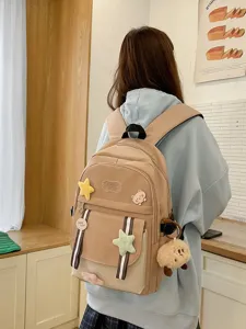 Stylischer beiger Schulrucksack mit niedlichen Pins, getragen von einer Studentin.