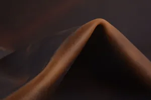 Detailopname die de rijke textuur, nerf en soepele valling van het bruine rundleer mooi toont.