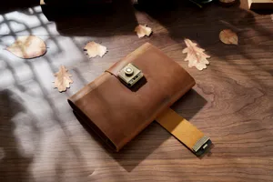 Vintage leather journal detail shot featuring brass combination lock and rustic wooden background.