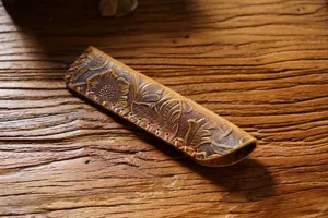Handmade vintage leather pen case detail, showing floral tooling and stitched edge craft.