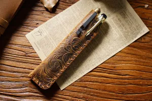 Close-up view of the handcrafted vintage leather pen pouch featuring intricate floral embossing and rustic texture.
