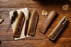 Close-up detail shot of handmade embossed leather pen pouch and vintage leather case design.