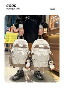 Detail von zwei großen weiß-beigen Schulrucksäcken mit süßen Pinguin-Anhängern für Schule.