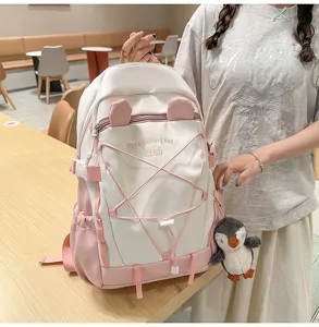 Detailansicht eines stilvollen rosa-weißen Schülerrucksacks mit einem süßen Pinguin-Anhänger