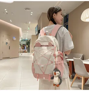 Großer pink-weißer Schulrucksack für Mädchen mit Ohren, getragen von einem Model im Café