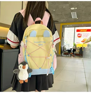Gelber Schülerrucksack mit Pinguin-Plüschanhänger an Person