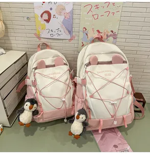 Detailansicht von zwei niedlichen rosa-weißen Studentenrucksäcken mit Pinguin-Plüsch-Anhängern