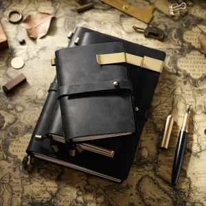 Vue détaillée d'un élégant carnet en cuir noir vintage avec clip en laiton et lanière.