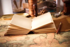 Primo piano dettagliato di taccuino in pelle vintage con pagine vuote su mappa antica.