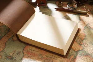 Vintage leather notebook detail shot, handmade brown journal sketch book open on antique map.