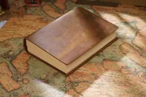 Close-up view of a vintage handmade leather journal on an old map background, showcasing rich texture.