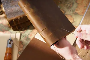 Hand stitching detail of vintage leather notebook showing craftsmanship and cowhide texture