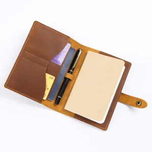 Handmade leather travel notebook detail view with card slots and pen holder inside.