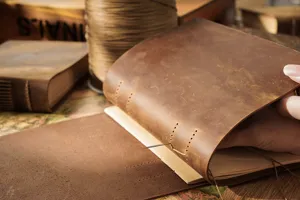 Handmade leather notebook detail showing vintage stitching and genuine cowhide texture craft.