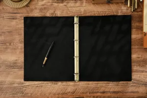 Vista dettagliata di taccuino A4 in vera pelle vintage con anelli metallici e penna stilografica.