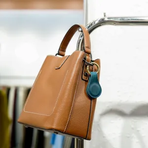 Brown leather handbag detail hanging on rack, premium material with fine stitching and metal hardware.