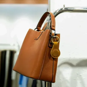Close-up detail of premium brown genuine leather bucket bag with metal hardware and strap.