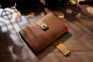 Retro genuine leather notebook with metal password lock displayed on dark wooden desk.