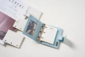 Close-up view of a light blue M5 mini 3-ring loose-leaf notebook with cute stationery props.