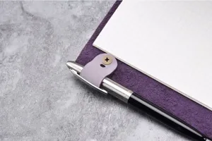 Vista dettagliata del diario in vera pelle viola dotato di pratico portapenne e carta a quadri.