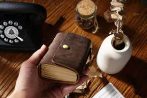 Gros plan du carnet de poche en cuir vintage fait main avec bouton en laiton sur bois.