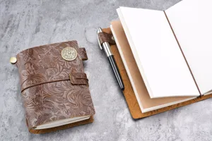Gros plan détaillé d'un journal en cuir gaufré vintage avec bouton décoratif et stylo.