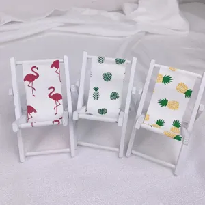 Detailansicht des Mini-Holzstrandstuhls als Handyhalter mit niedlichem Flamingo- und Ananasdruck.