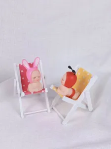 Mini-Harz-Puppe mit hölzernem Strandstuhl Detailaufnahme, süßes Tierhut Ornament Nahaufnahme.