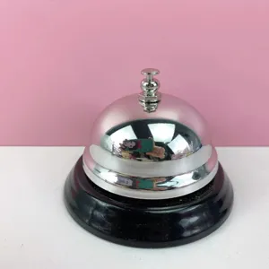 Detalles en primer plano de la campanilla de servicio de metal plateado con base negra elegante.