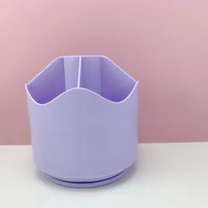 Gros plan de l'organisateur de bureau violet pour stylos et papeterie diversifiée.
